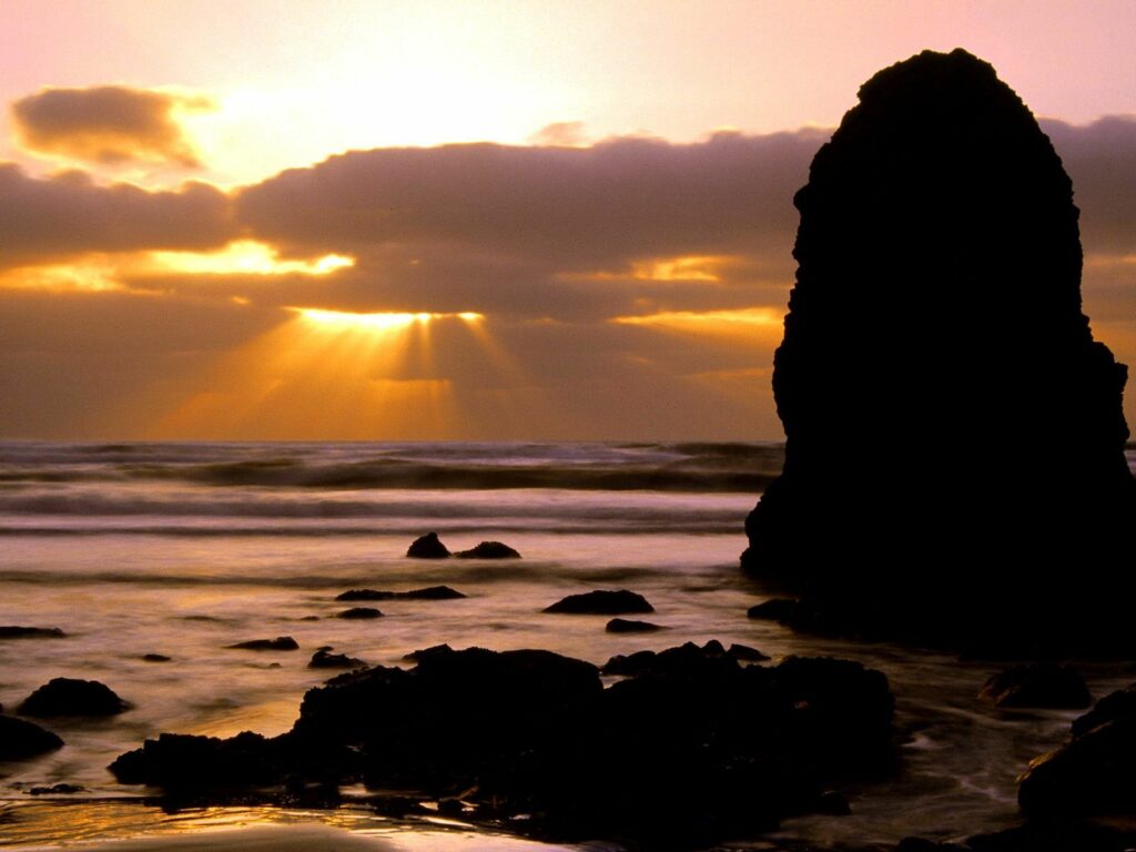 Dramatic Oregon seascape wallpaper with rugged stones and golden sunset over crashing waves
