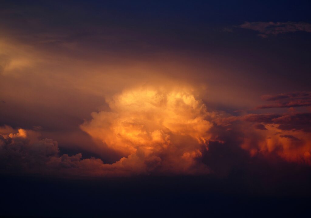 Dramatic overcast sky with dark clouds lit by warm golden light textured wallpaper background