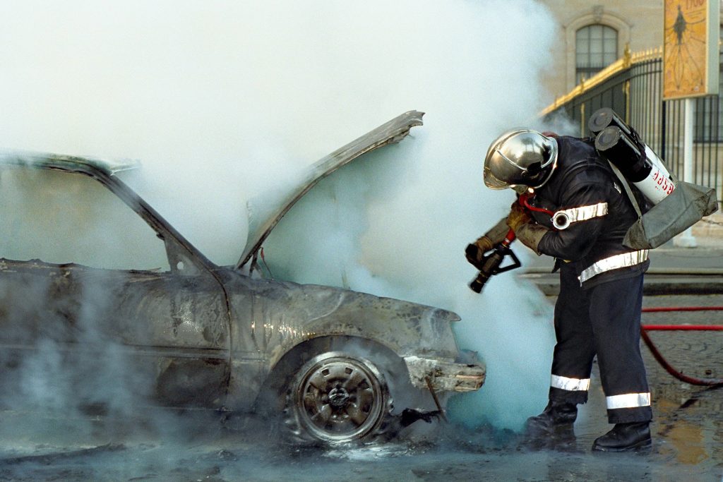 Paris Fire Brigade firefighter extinguishing car fire in high-contrast emergency scene wallpaper