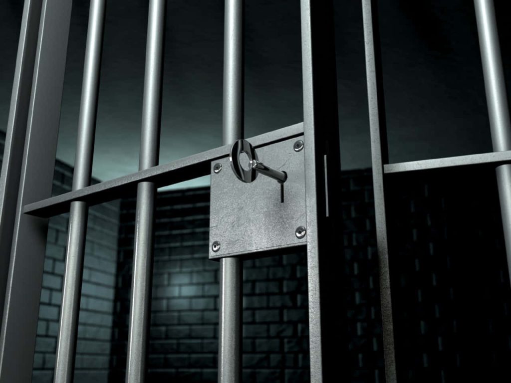 Close-up of prison cell gate with steel bars and key in lock dark moody jail wallpaper background