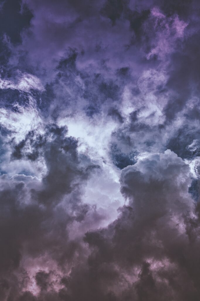 Dramatic purple and white clouds in a vibrant sky creating a moody and dynamic wallpaper background