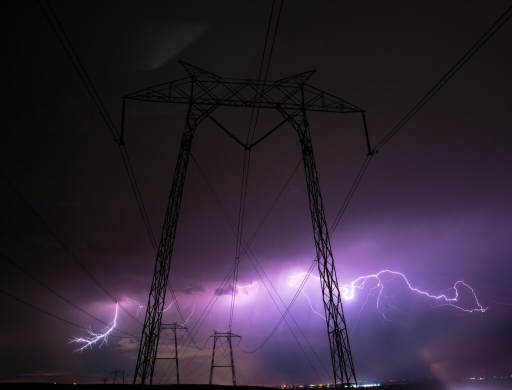 Purple and white lightning storm over silhouetted power line towers at night dramatic sky wallpaper