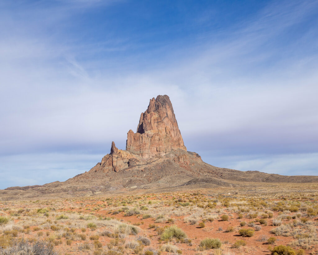 Dramatic rock formation over prairie under blue sky with wispy clouds scenic natural landscape Wallpaper