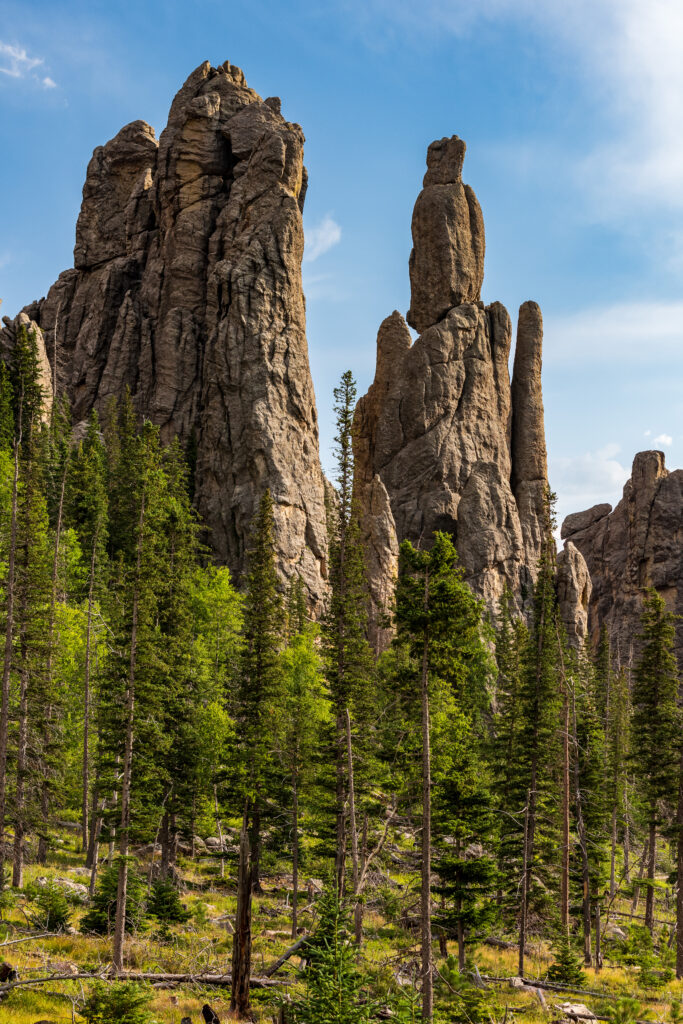Dramatic towering rock formations above lush green pine forest under clear blue sky nature wallpaper