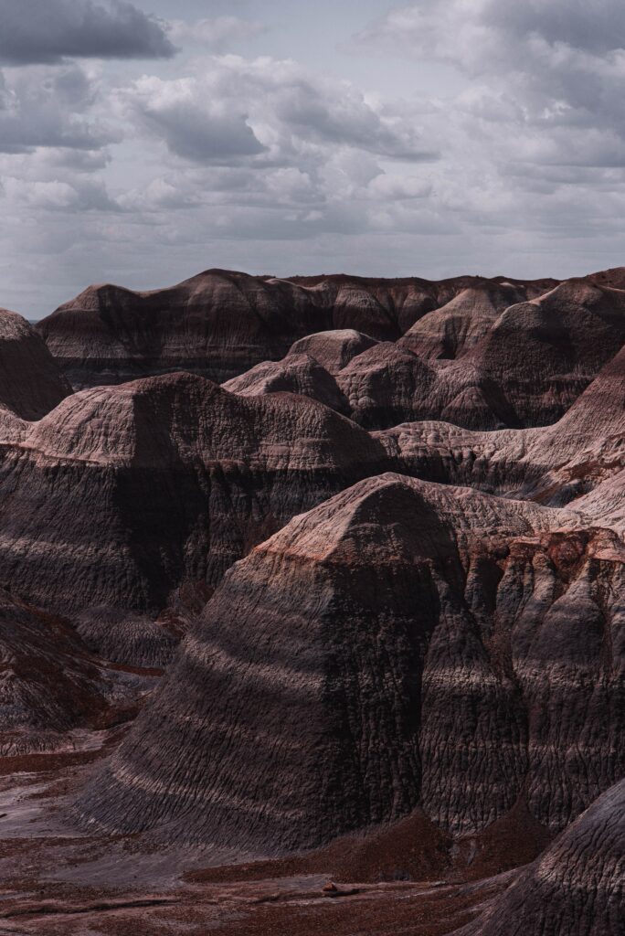 Dramatic layered rock formations with textured stone under a cloudy sky rugged natural landscape wallpaper