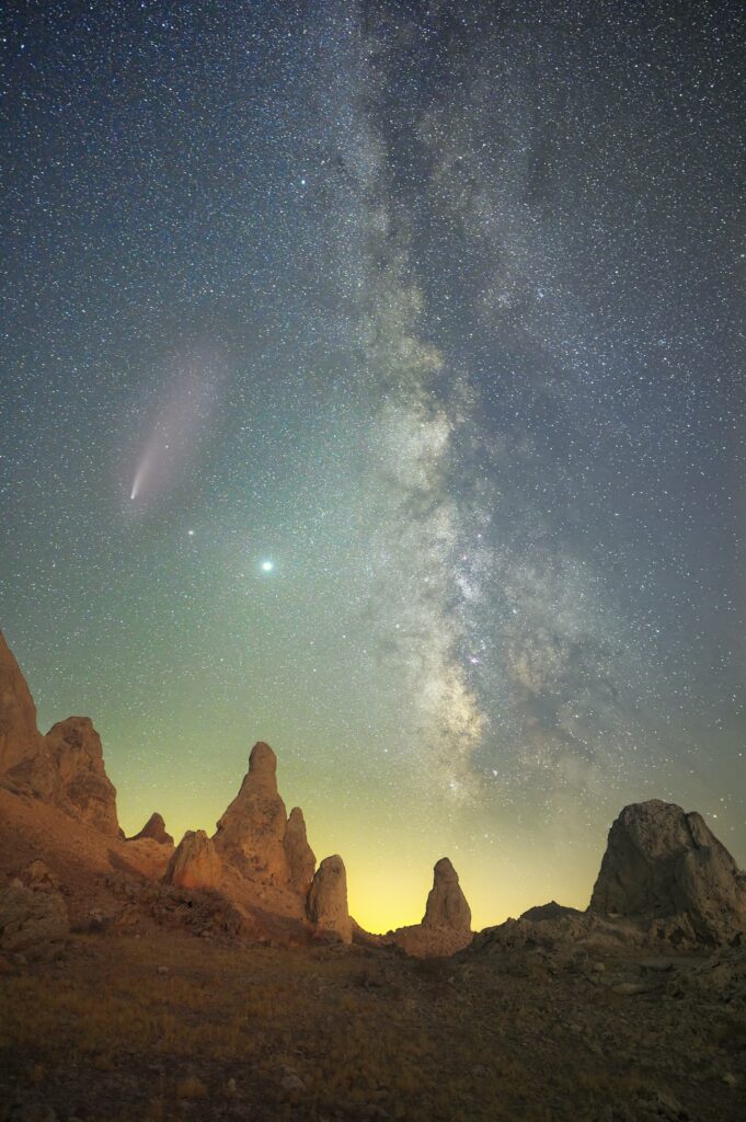 Dramatic rock formations under a vibrant starry sky with Milky Way and glowing nebula background Wallpaper