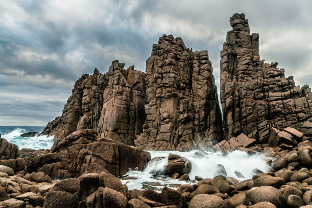Dramatic rocky cliffs and turbulent crashing waves on a rugged coastal seashore landscape wallpaper