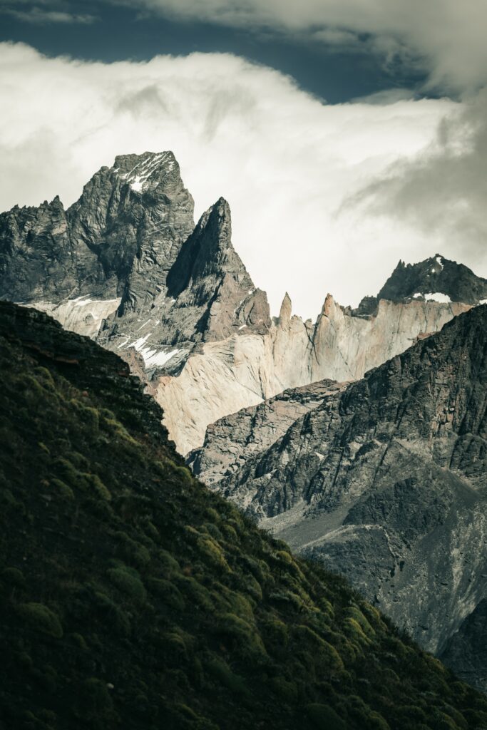 Dramatic rocky mountains with swirling clouds and green slopes nature landscape wallpaper background