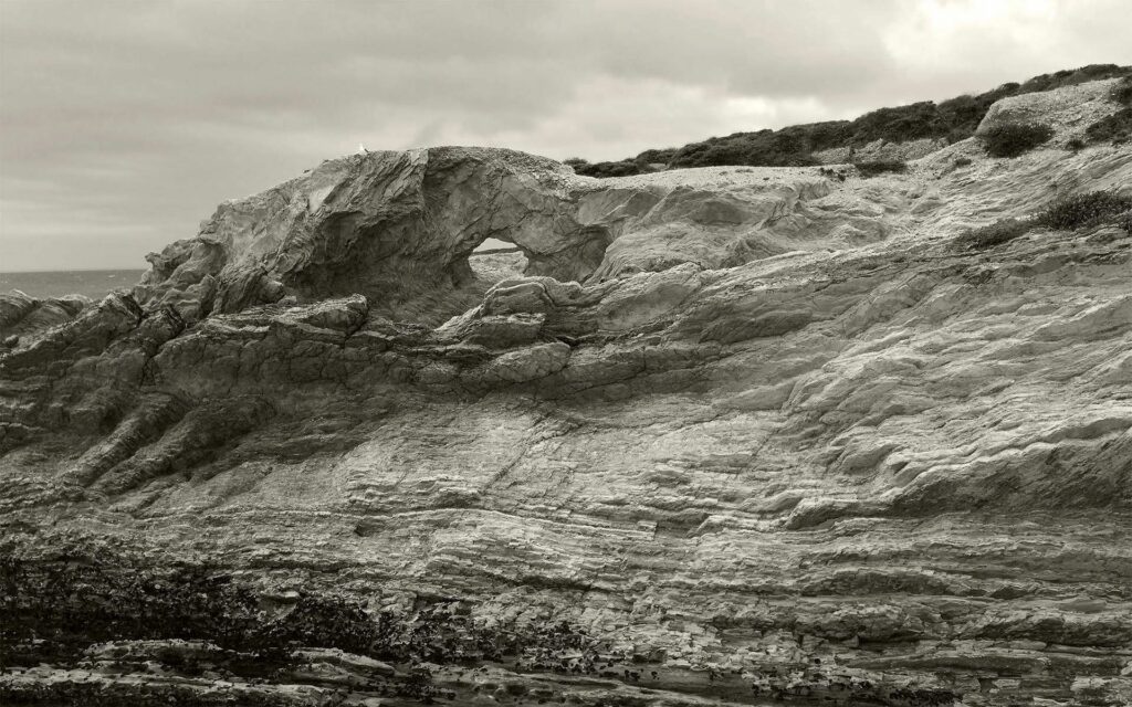 Grayscale wallpaper of rocky mountainside with unique stone formations and textured layers