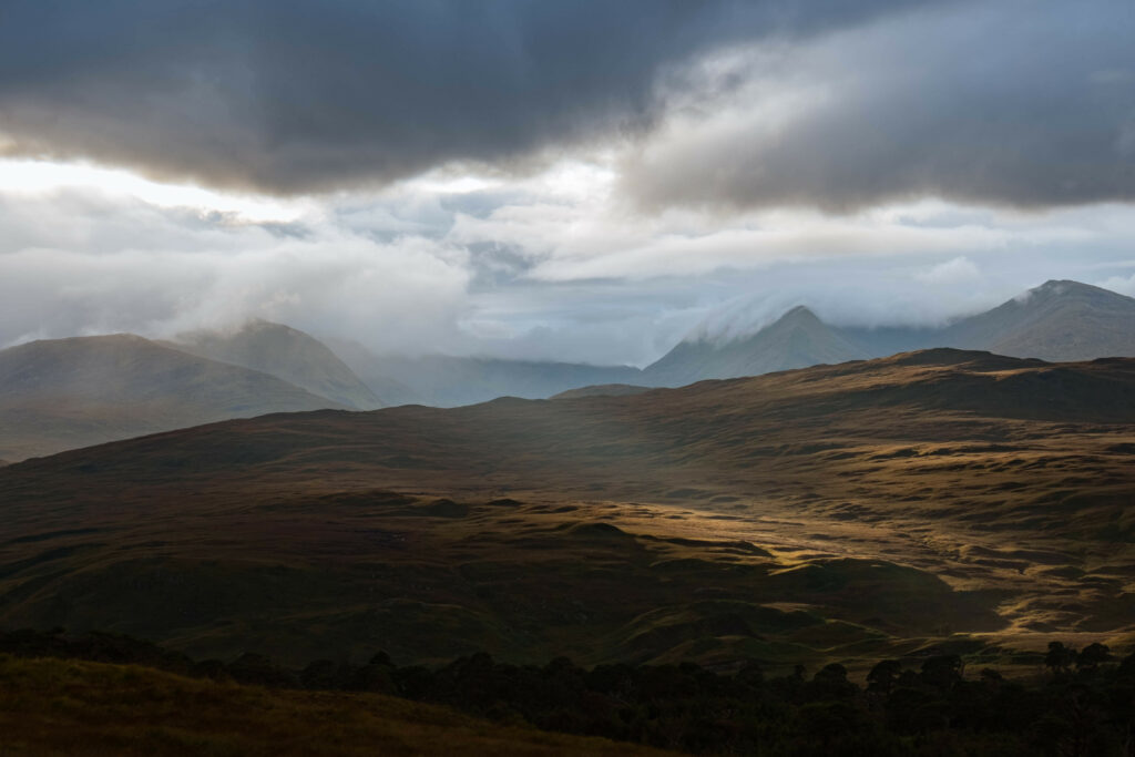 Dramatic mountain landscape with rolling valleys under moody cloudy sky earth tone wallpaper