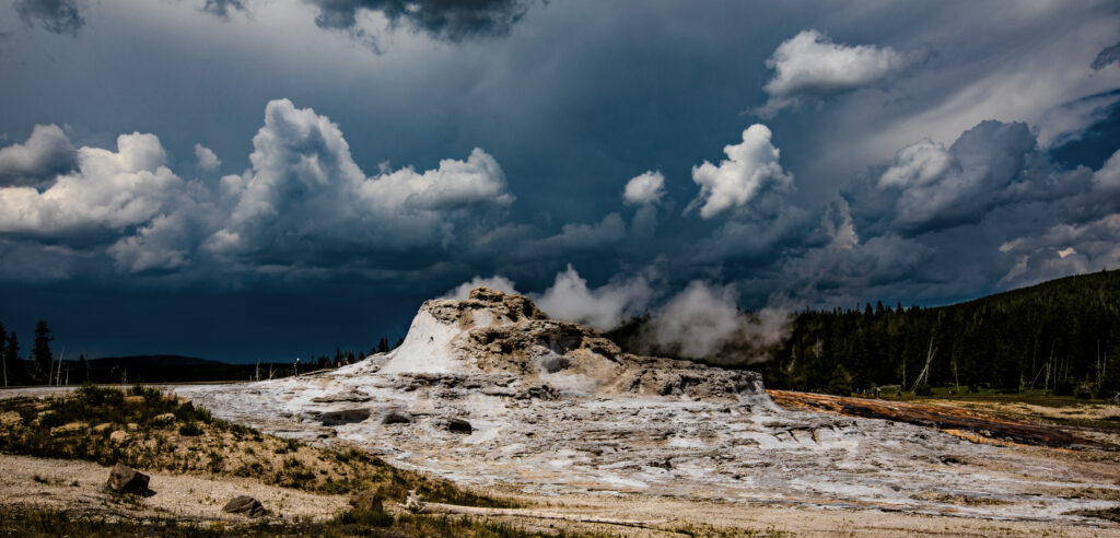 Rugged mountain rock with dark swirling clouds over dense forest natural dramatic wallpaper
