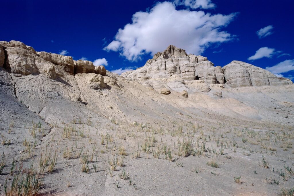 Dramatic sandy mountains under deep blue sky with clouds and sparse vegetation Asian desert wallpaper