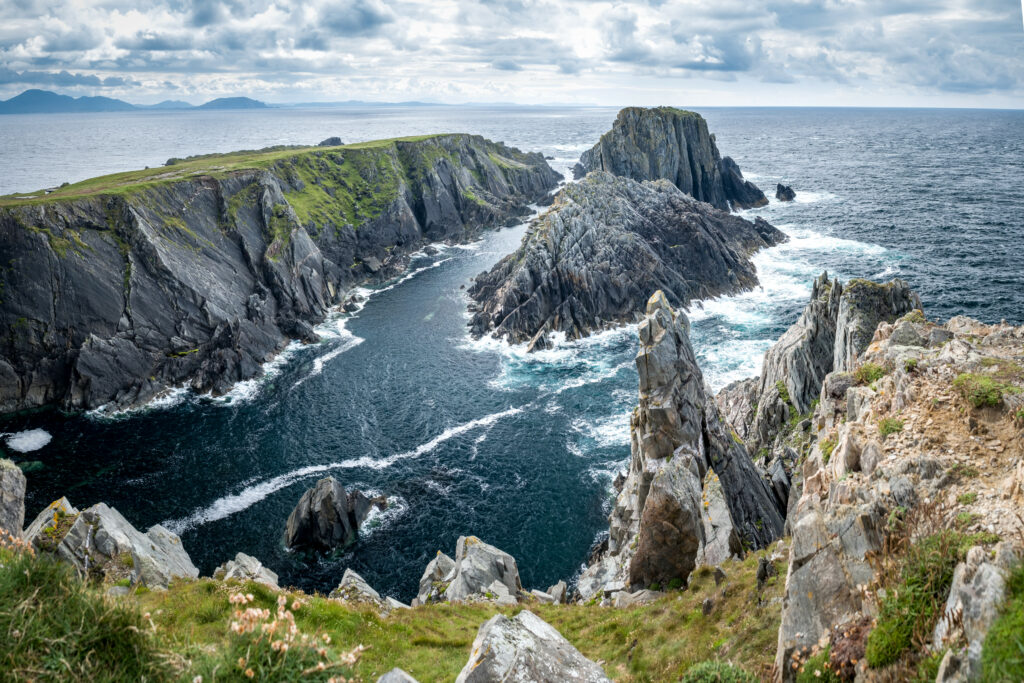 Dramatic seacoast with rugged rocks foamy waves lush green grass and vibrant blue sea wallpaper