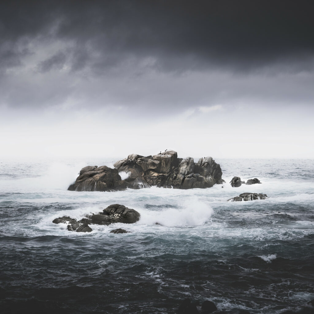 Dramatic seascape with stormy sky crashing waves on rugged rocks wallpaper background