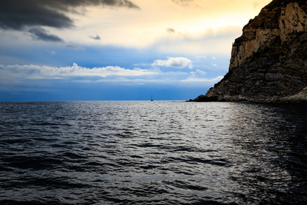 Dramatic seascape wallpaper with rugged rock cliff waves and glowing sunset sky background