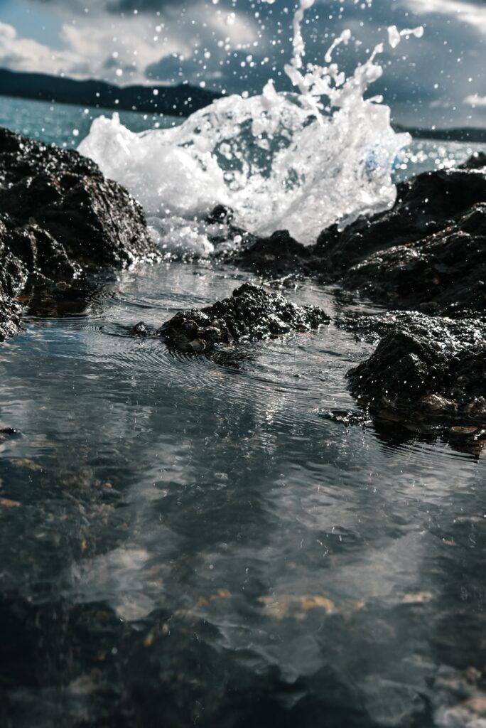 Dramatic seascape with crashing ocean waves on rugged rocks under moody sky wallpaper background