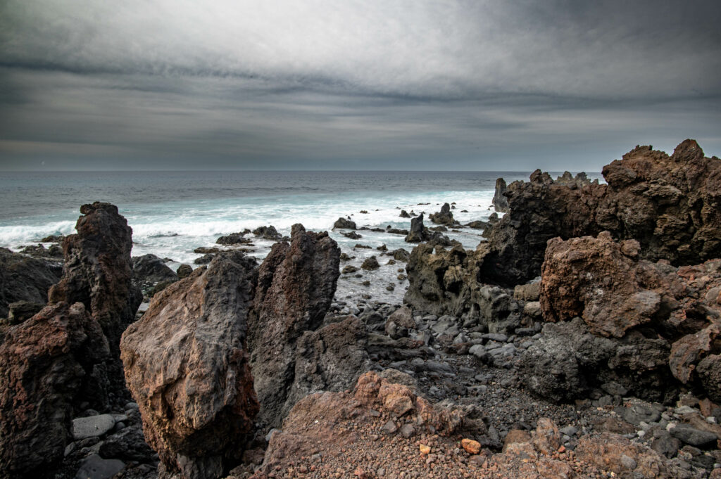 Dramatic seascape with rugged rocks gray brown blue tones moody sky and endless horizon wallpaper