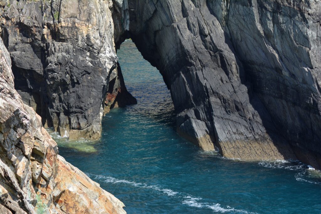 Dramatic seaside cliff with towering rock arches over deep blue water rugged coastal wallpaper