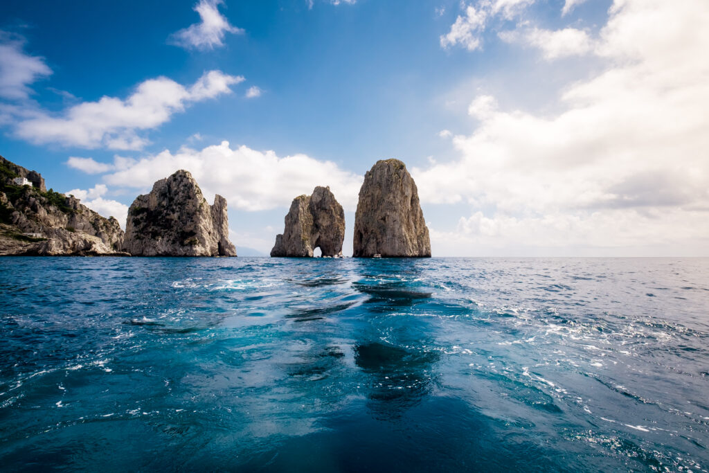 Dramatic seaside cliffs and towering rock formations over deep blue ocean under vibrant sky wallpaper