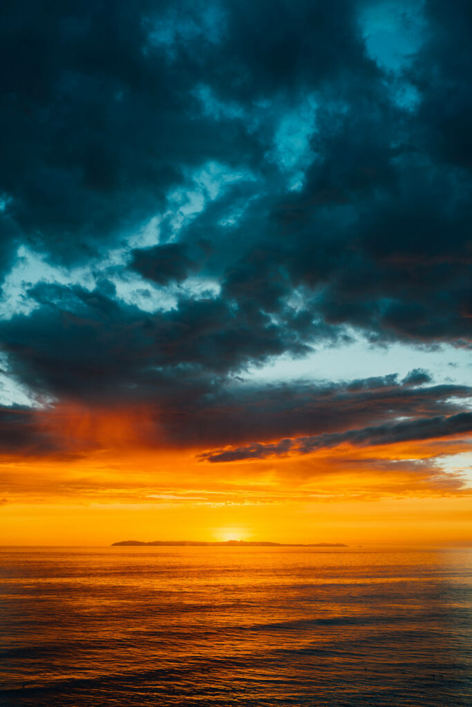 Moody Skies: Captivating Sun Setting Over the Turbulent Ocean - HD Mobile Wallpaper