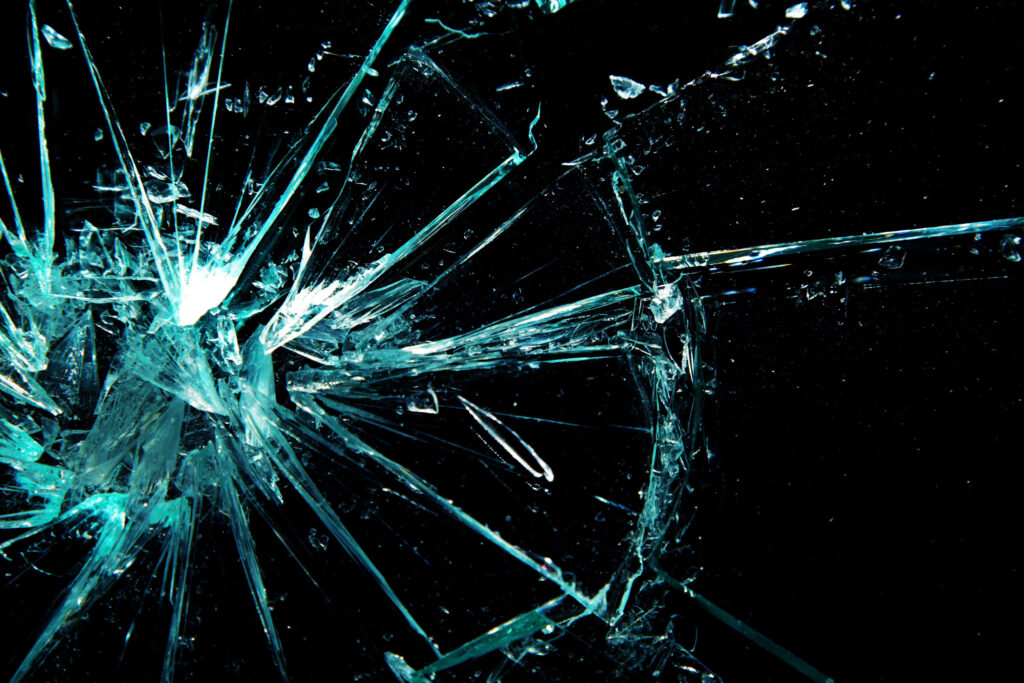 Broken glass wallpaper with sharp blue cracks on black background modern chaotic texture
