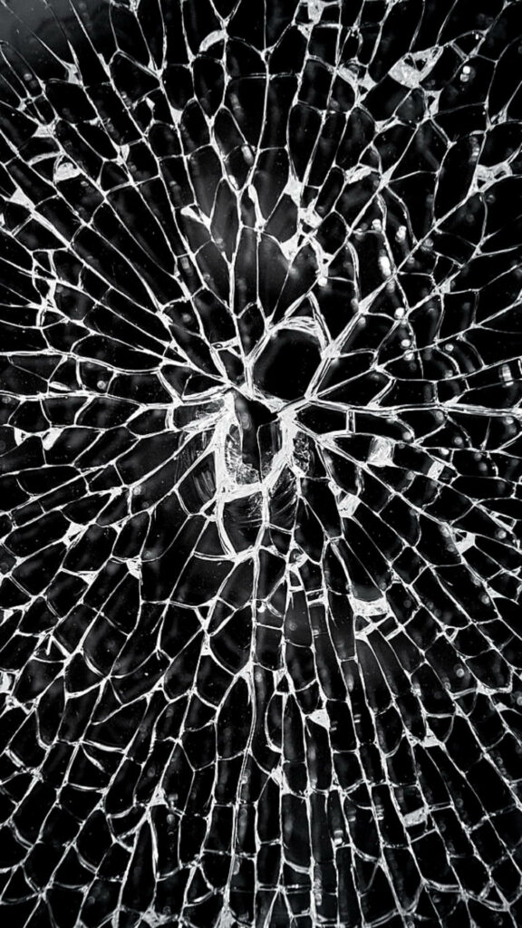 Abstract shattered glass wallpaper with intricate cracks radiating from center on dark background