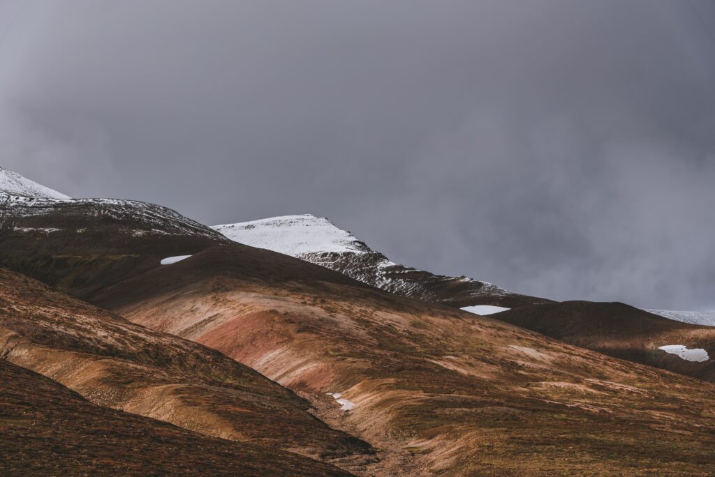 Snow-dusted hills near Akureyri Iceland with moody sky and earthy brown slopes wallpaper background
