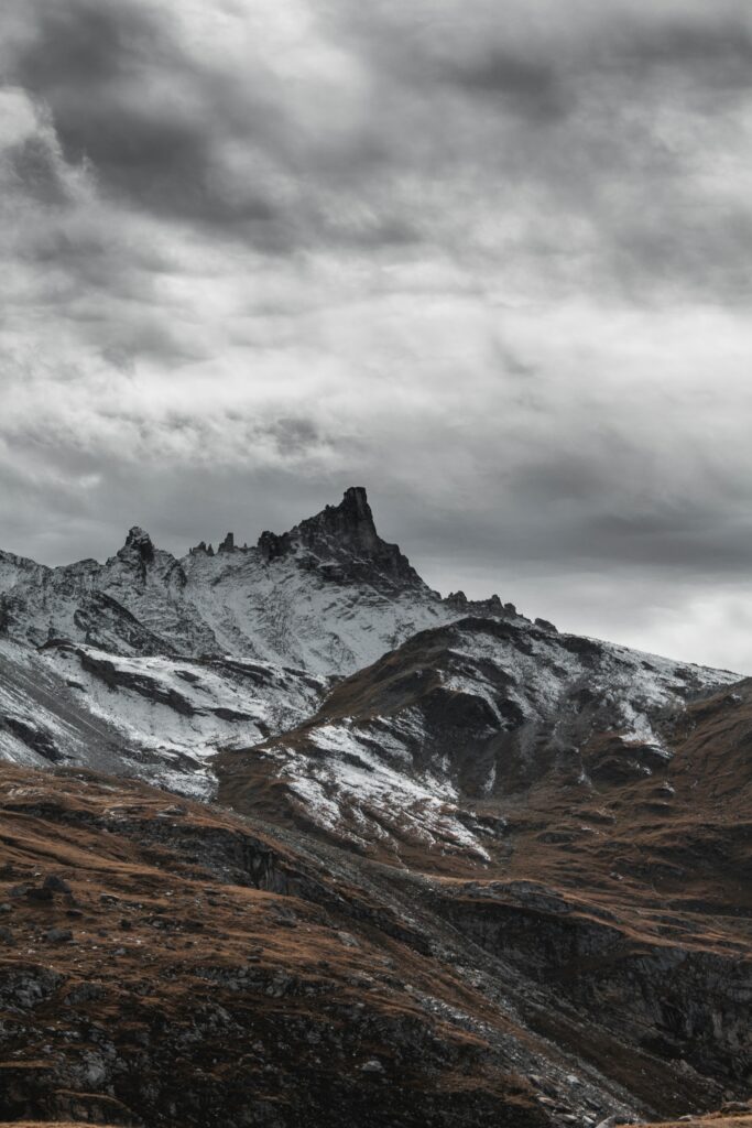 Dramatic rugged mountain landscape with snow dusted peaks under moody overcast sky wallpaper