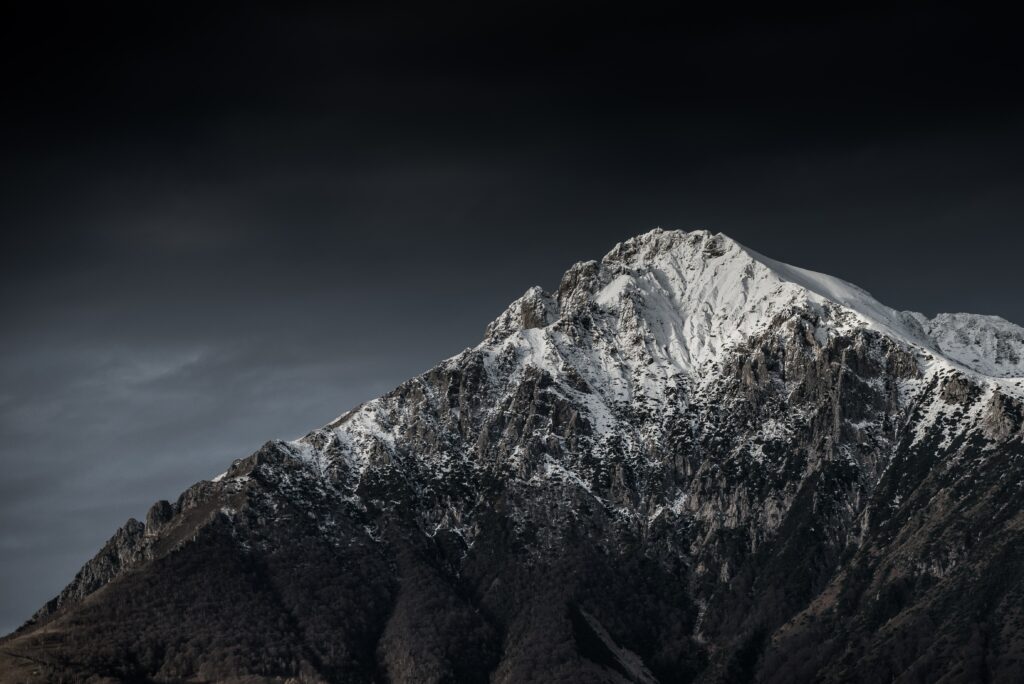 Rugged Italian mountain peak with fresh snow under moody night sky dramatic landscape wallpaper