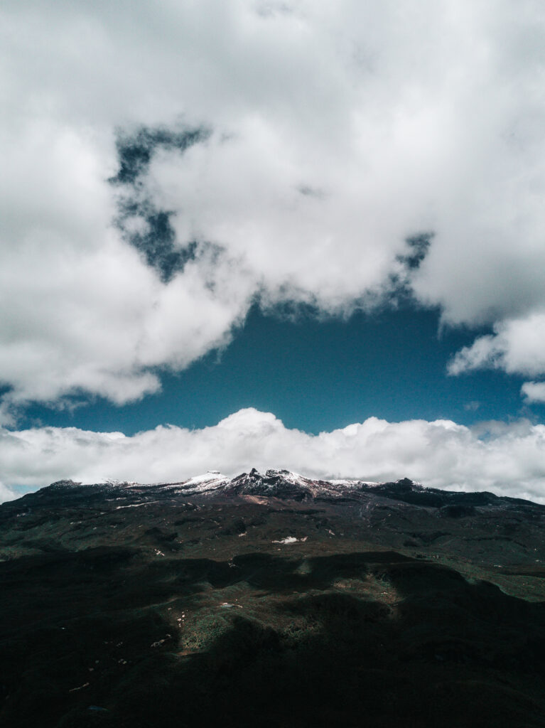 Dramatic mountain landscape with snow-capped peaks and billowing clouds under vibrant blue sky Wallpaper