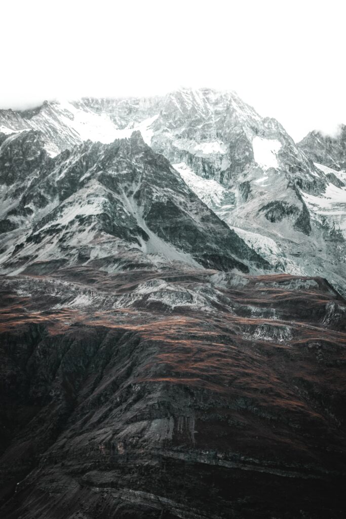 Aerial view of rugged snow-dusted mountain peaks with earthy brown slopes scenic wallpaper background