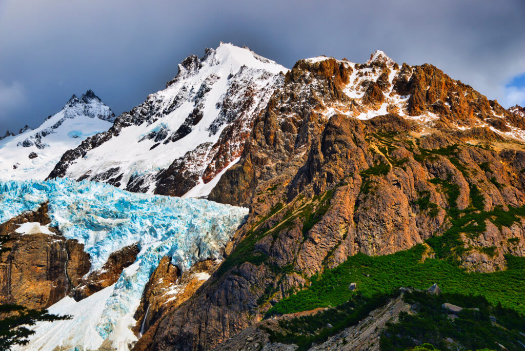 Dramatic snow-capped mountain peaks with rugged rocky terrain and vibrant natural colors background Wallpaper