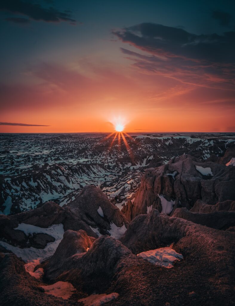 Dramatic sunset over snowy rugged mountains with warm glow and vibrant wintry sky background Wallpaper