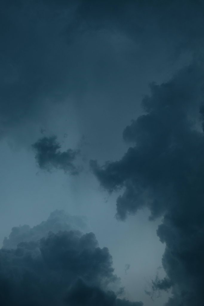 Dramatic storm clouds in deep slate blue and charcoal create a calming aesthetic wallpaper background
