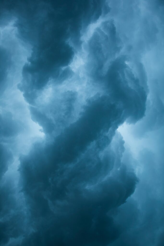Dramatic storm clouds swirling in deep blue and gray sky creating moody atmospheric wallpaper