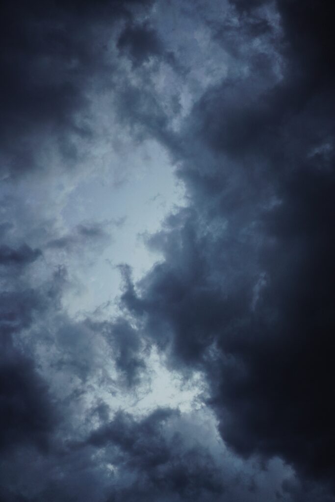 Dramatic storm clouds swirling in deep blue and grey sky creating moody intense atmosphere Wallpaper