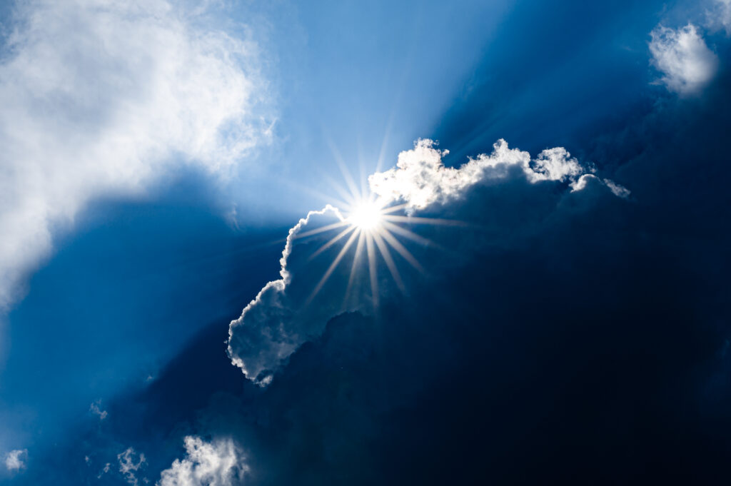 Dramatic clouds with bright sun rays and deep blue sky perfect uplifting wallpaper background