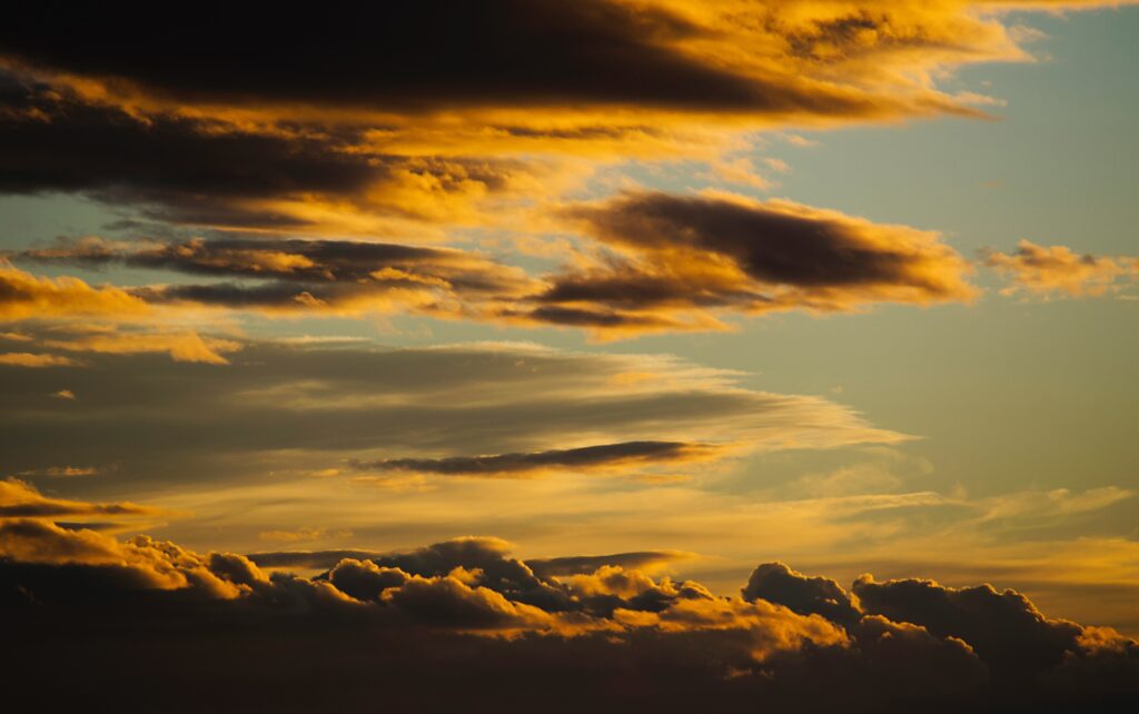 Dramatic sunset clouds glowing with warm golden and deep orange tones in dusk sky wallpaper