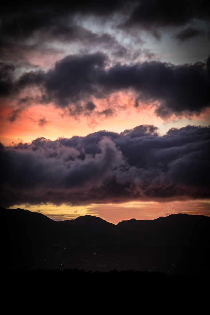 Dramatic sunset with dark mountains and colorful clouds over rolling hills nature wallpaper