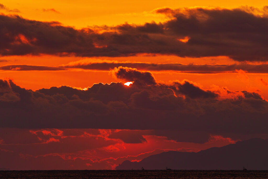 Dramatic sunset with dark clouds orange red sky over calm sea tranquil atmospheric wallpaper background