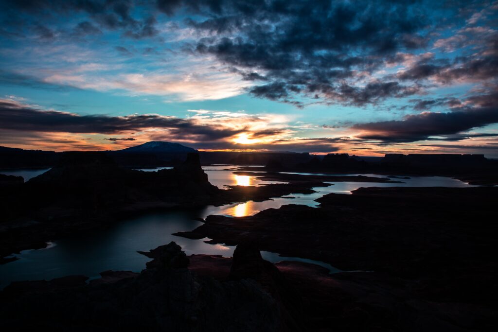 Sunset over rugged rocks flooded with water vivid sun rays and textured clouds reflecting colors Wallpaper