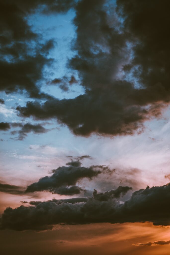 Dramatic sunset sky with dark clouds and vibrant orange pink blue hues nature wallpaper background