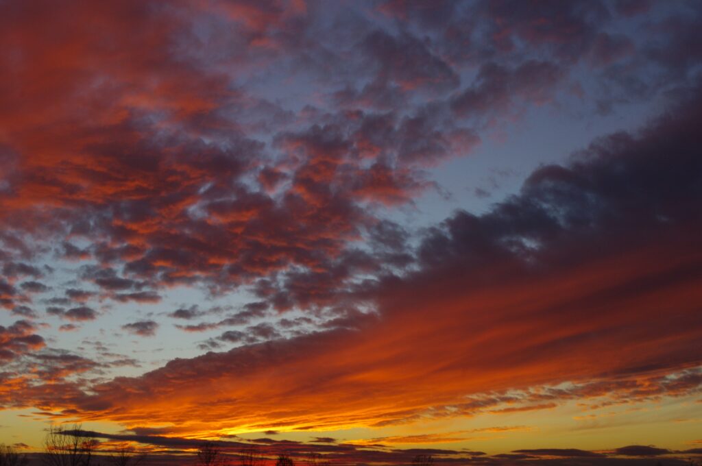 Dramatic sunset sky with vibrant orange and deep blue clouds over a serene horizon wallpaper background