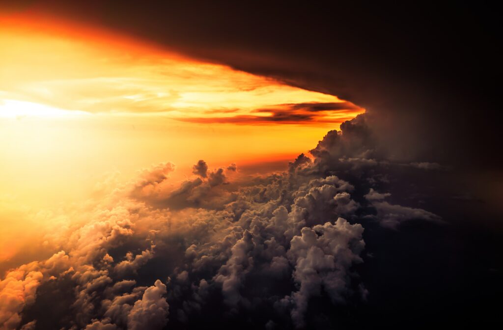 Dramatic sunset sky with golden orange porous clouds and dark overcast shadows wallpaper background