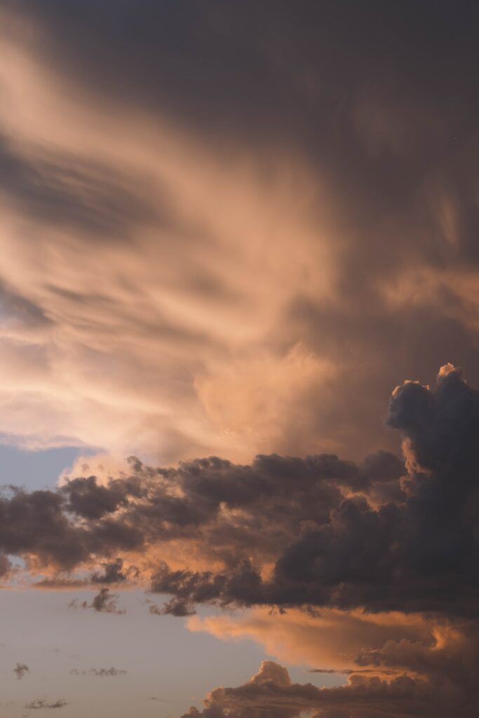 Dramatic sunset sky with swirling gray and golden clouds creating a dynamic textured wallpaper