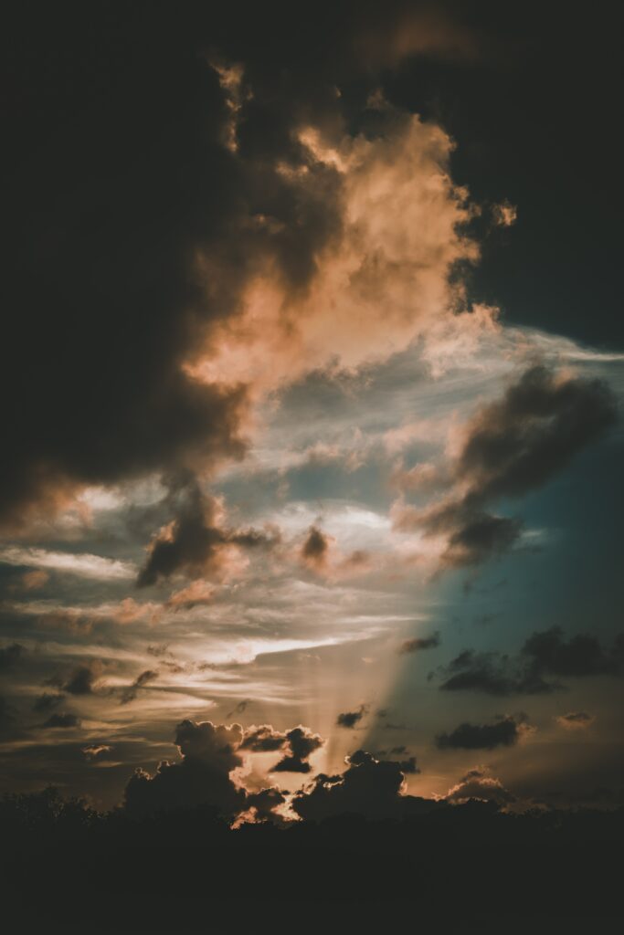 Dramatic sunset wallpaper with golden rays through moody clouds over deep blue and orange sky