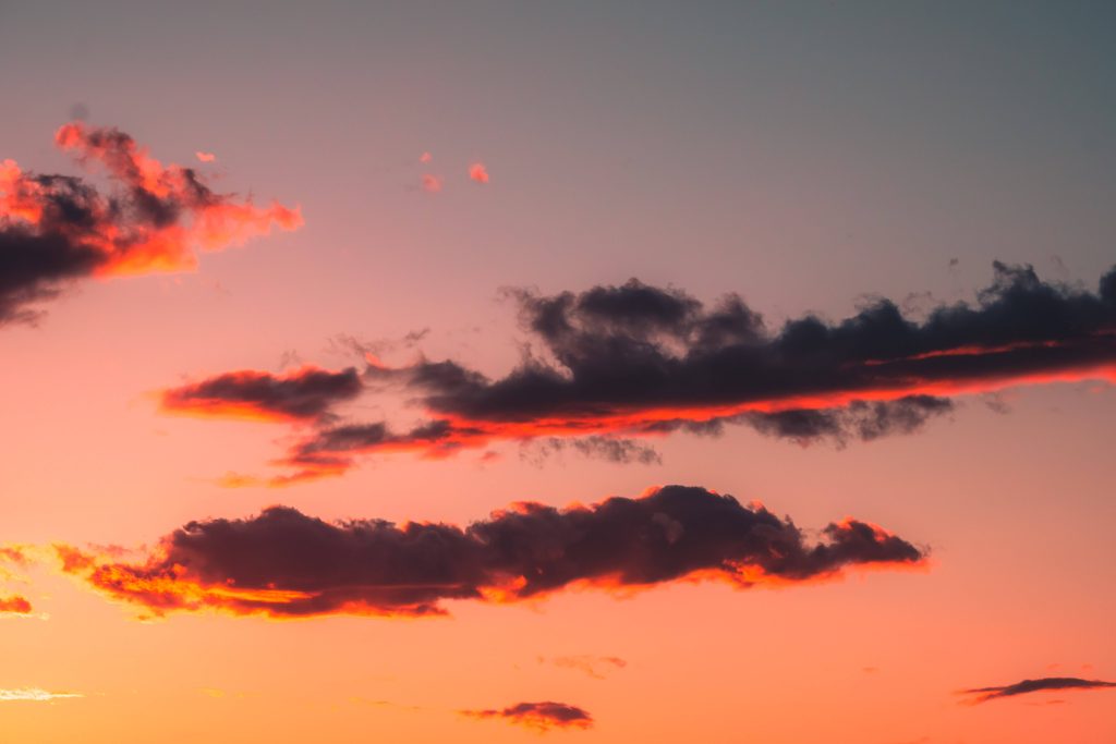Sunset wallpaper with dark clouds and vibrant orange peach pink gradient sky background