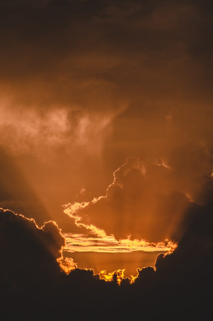 Dramatic sunset with glowing rays and golden tones behind dark clouds cinematic wallpaper background