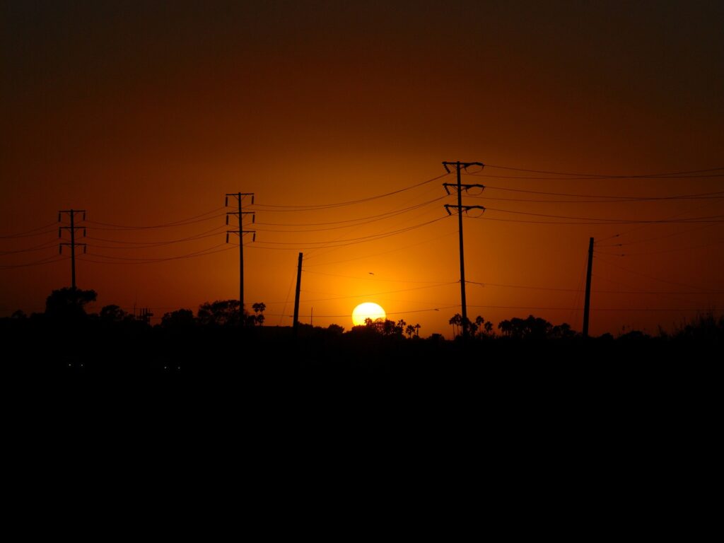 Dramatic sunset with warm orange sky and silhouetted power lines minimalist tranquil wallpaper
