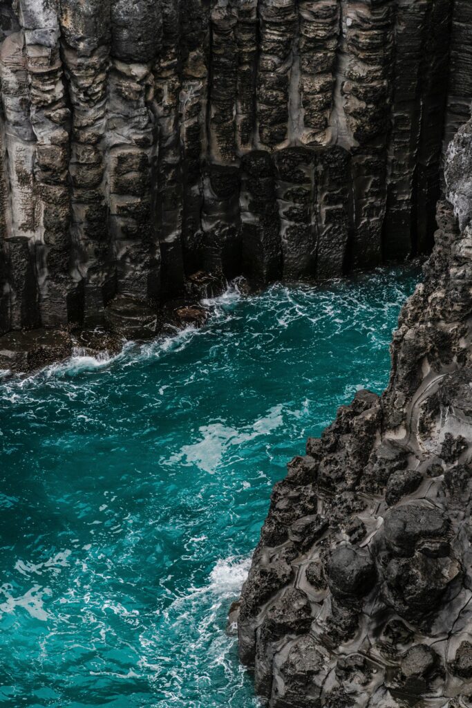 Turquoise water rushing through rugged towering rocks with foamy waves vibrant nature wallpaper